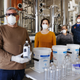 Man holding bottle of hand sanitizer in distillery factory setting
